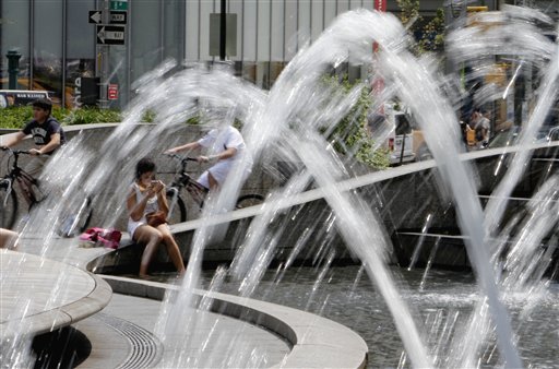 A woman freshens her make-up as she cools her feet in the fountain New York's Columbus Circle, Thursday, July 21, 2011. New York City is roasting under a potentially dangerous brew of heat and humidity, as officials warn the elderly and chronically ill to find cool refuges.(AP Photo/Richard Drew)
