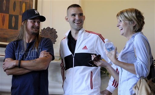 In this Saturday, Aug. 18, 2012 photo, Dana Dumar, right, tries to find the words during media interviews as she stands with her husband, Davin Dumar, center, and Kid Rock, in the model house similar to the one that will be built for the couple in Macomb Township, Mich.  Kid Rock joined Dan Wallrath, founder of Operation Finally Home, and representatives of the Pulte Group to present Dumar , a veteran of Afghanistan who lost his leg and severely injured his arm in combat, and his wife Dana, with a free new home. (AP Photo/Detroit News, Todd McInturf)