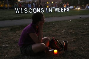 A woman sits with a candle during a vigil for the victims of the Sikh Temple of Wisconsin shooting, in Milwaukee, Sunday, Aug 5, 2012. An unidentified gunman killed six people at a Sikh temple in suburban Milwaukee in a rampage that left terrified congregants hiding in closets and others texting friends outside for help. The suspect was killed outside the temple in a shootout with police officers. (AP Photo/Jeffrey Phelps)