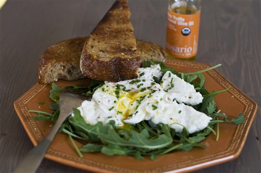 In this image taken Dec. 3, 2012, poached eggs over ricotta cheese on arugula are shown served on a plate in Concord, N.H. (AP Photo/Matthew Mead)