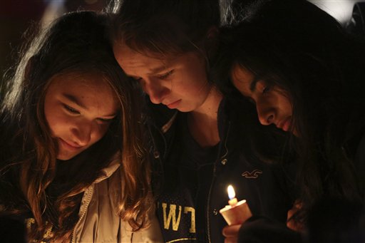 Kate Suba, left, Jaden Albrecht, center, and Simran Chand pay their respects at one of the makeshift memorials in honor of the victims of the Sandy Hook Elementary School shooting, Sunday, Dec. 16, 2012, in Newtown, Conn. A gunman opened fire at the school on Friday, killing 26 people, including 20 children before killing himself on Friday. (AP Photo/Mary Altaffer)