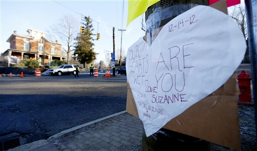 A sign on a post shows support for the victims of a gunman who opened fire inside Sandy Hook Elementary School a day earlier as police officers stand at a road block, Saturday, Dec. 15, 2012, in Sandy Hook village of Newtown, Conn. The massacre of 26 children and adults at Sandy Hook Elementary school elicited horror and soul-searching around the world even as it raised more basic questions about why the gunman, 20-year-old Adam Lanza, would have been driven to such a crime and how he chose his victims.  (AP Photo/Julio Cortez)