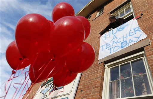 Gary Seri, general manager at the Stone River Grille, hangs a message written on a table cloth in honor of the teachers who died along with students a day earlier when a gunman open fire at Sandy Hook Elementary School, Saturday, Dec. 15, 2012, in the Sandy Hook village of Newtown, Conn. Seri, who put up red balloons that were not used when a sweet 16 party was canceled the night before in light of the massacre, said the teachers were scheduled to have their holiday party at his restaurant. The massacre of 26 children and adults at Sandy Hook Elementary school elicited horror and soul-searching around the world even as it raised more basic questions about why the gunman, 20-year-old Adam Lanza, would have been driven to such a crime and how he chose his victims.  (AP Photo/Julio Cortez)