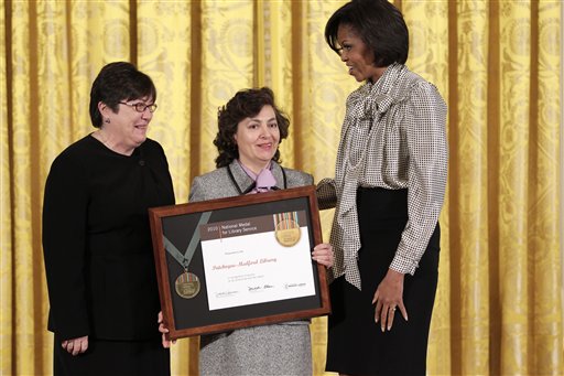 First lady Michelle Obama presents a 2010 National Medal for Museum and Library Service to Dina McNeece, the director of Patchogue-Medford Library, Patchogue, N.Y., center, and community member, Zheni Velasquez, left, during an East Room ceremony Dec. 17, 2010, at the White House in Washington.  The National Medal is the nation's highest honor for museums and libraries that make extraordinary civic, educational, economic, environmental, and social contributions. (AP Photo/J. Scott Applewhite)
